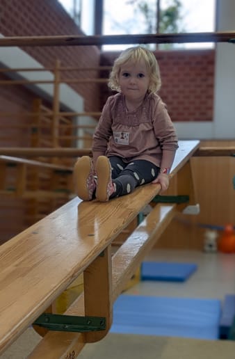 Kleines Mädchen auf einer schrägen Bank