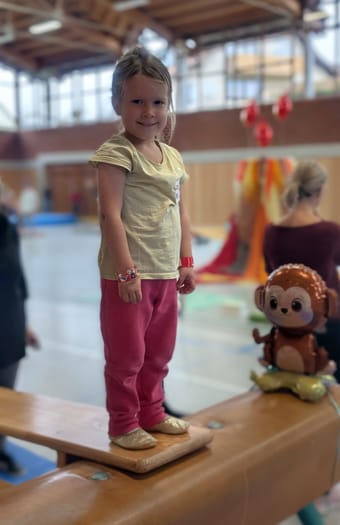 Mädchen balanciert neben einem Stoffaffen
