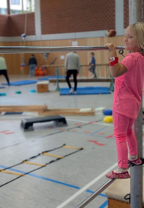 Mädchen hangelt sich an einer Stange entlang