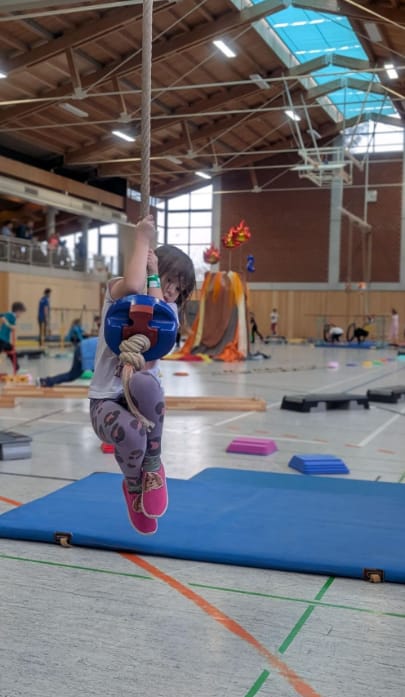 Kind schwingt am Seil über die Matten